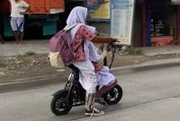 Ilustrasi: Anak sekolah mengendarai sepeda motor listrik