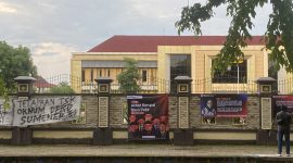 Foto : Banner aksi bisu Dear Jatim dipasang di pagar Mapolres Sumenep, menuntut penegakan hukum tegas atas dugaan korupsi di Kabupaten Sumenep, Selasa (9/12/2025)