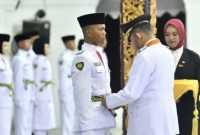 Foto: Bupati Sumenep Achmad Fauzi Wongsojudo memasangkan kendit kepada perwakilan Paskibraka 2026 saat prosesi pengukuhan di Pendopo Agung Keraton Sumenep