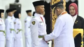 Foto: Bupati Sumenep Achmad Fauzi Wongsojudo memasangkan kendit kepada perwakilan Paskibraka 2026 saat prosesi pengukuhan di Pendopo Agung Keraton Sumenep